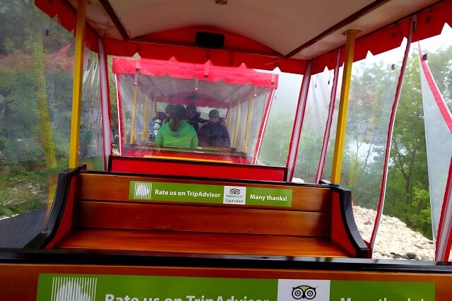 Turyści pociąg, którym przewożą do wejścia do jaskini